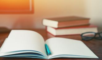 notebook with pen and books at workplace