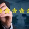 Review increase rating performance and classification concept. Businessman draw five yellow stars to increase rating of his company office in background.